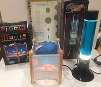 Magic Spinning Lamp, blue Lava Lamp, green beaded curtain shown together with packaging visible