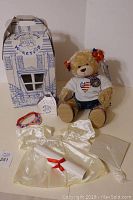 Build-A-Bear bear with graduation accessories and boxes arranged together