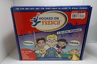 Image of the front of the boxed Hooked on French program showing the title, 3-level program, price sticker, and cartoon children characters.