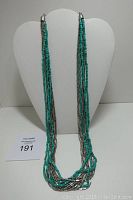 Full front view of the necklace displayed on a white bust stand showing length and strand layering