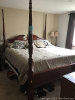 Full view of the wooden four poster king size bedframe set up in bedroom, showing headboard, footboard, and four corner posts