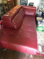 Red leather sectional sofa, showing tufted seat cushions and adjustable back headrest with storage compartments under headrests.