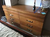 Front view of solid wood eight drawer dresser with metal handles, showing wood finish and condition.