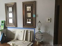 Photo showing the glass lamp with clear and frosted glass body and tarnished spots, and two gold-tone rectangular frames each containing six small mirrors.