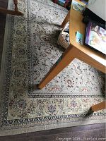 Photo showing the full area rug under a wooden table, detailing the floral pattern and colors.