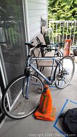 Marin road bike on porch next to chairs, gray frame with black seat and black handlebar grips.
