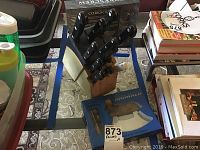 Wooden knife block with ten Laser Plus knives and one additional knife with black handles, placed on a table.