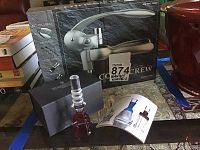 Photo showing the professional corkscrew box with the lever-style metallic gray corkscrew device and additional accessories, plus the Waterford Crystal wine stopper in a black Waterford box, along with a product brochure.