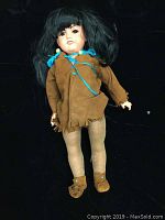 Full body standing view of vintage Armand Marseille porcelain doll, showing outfit and black wig with bangs