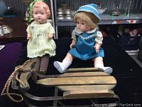 Two 18-inch composition dolls and a wood and metal sleigh on display.