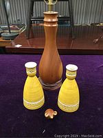Full view of the wooden lamp, ceramic candle holders, and wooden mouse on purple surface.