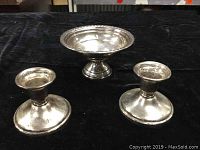 Photo showing the pair of Birks sterling silver candlesticks and the weighted pedestal candy bowl together on a black surface.