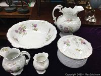 Five-piece Johnson Brothers semi-porcelain washstand set with floral decals and gold accents on a dark surface.