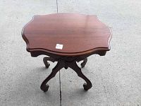 Front angled view of antique mahogany side table showing scalloped top and curved legs