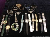 Photo showing full collection of 20 assorted quartz wristwatches arranged on black background. Includes various styles with metal, leather and fabric bands, shapes, and colors.