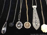 Lots of 5 necklaces with pendants on black fabric showing front detail