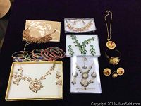 Full collection showing all jewelry pieces on black background including necklaces, earrings, multicolored bangles, bracelet, and ring.