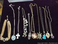 Full view of all 10 necklaces lined up horizontally on a black cloth background