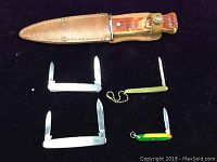 Top view showing all five knives including the Imperial hunting knife in leather sheath and four small pocket knives with blades extended.