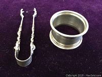 Napkin ring and sugar tongs on purple background showing overall set.