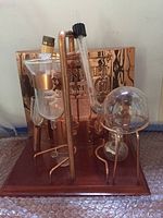 Distillation setup showing copper and glass components mounted on wooden base.