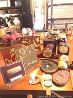 Photo of small clocks and herb tiles arranged on a table with additional decorative items including starfish and ceramic figures.