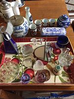 Photo showing array of blue and white pottery including large jar labeled Amphora, sake set, and glass decorative items on fruit motif tray
