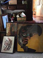 Photo showing the two framed prints with a larger print in warm earth tones and a smaller black and red print.