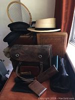 Overview of the lot showing briefcases, hats, wallets and badminton racket