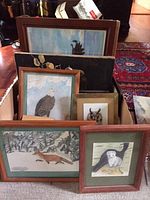 Photo showing multiple framed wildlife art pieces stacked close, featuring birds and a fox.