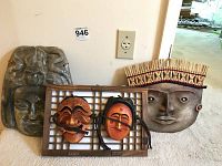 Photo showing full lot with Mayan stone mask on left, large South Korean wooden mask with headpiece on right, and two smaller South Korean masks mounted on frame in front.