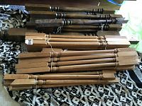 Multiple oak wood spindles and stair banisters bundled together, showing variety in shapes and finishes.