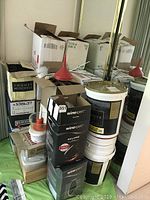 Stack of boxes including Winexpert wine kits, plastic buckets with lids, and funnels used for wine making.