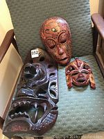 Three Pacific Island wood masks on chair, showing size and carved detail