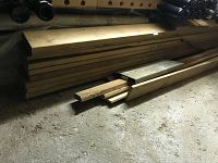 Wide view of pile of dry seasoned wood boards stacked against wall