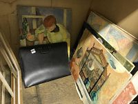 Photo showing three ordinal art paintings stacked against a wall with a black art bag in front.