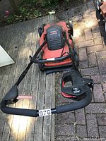Front angled view of the orange Lawn Hog electric lawn mower showing the detached black handle with grips and lever.