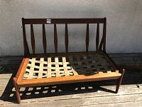 Front view of teak bench frame showing vertical slat backrest and woven webbed seat support in two colors.