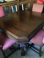 Top view of the square mahogany dining table with carved apron and pedestal base.