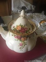 Porcelain tea pot with floral pattern and gold trim on a surface