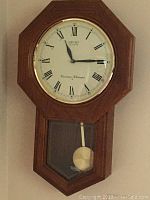 Full view of wooden octagonal Seiko wall clock showing clock face and pendulum.