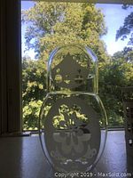 Image of the transparent glass carafe shaped like a Matrushka doll with frosted face and flower pattern on body.