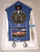 Blue Camaro-themed cuckoo clock with speedometer dial, red Camaro car on top, Camaro images below, shown in foam packaging with accessory bag.