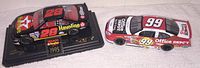 Front angle showing the top and side views of the black #28 Havoline and white/red #99 Office Depot die cast race cars on a plain surface