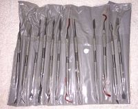 Set of 12 stainless steel wax carving tools in clear plastic slots within a gray carrying pouch.