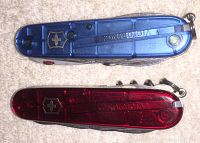 Top view of blue and red translucent Victorinox Swiss Army knives showing brand and translucent handles.