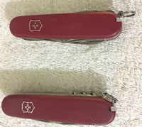 Top view of two red matte finish Victorinox Swiss Army knives placed on white fabric, showing logo on handle.