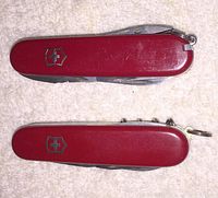 Top-down view showing the two red Victorinox Swiss Army Knives with logo visible, one larger with several folded tools and one smaller with a key ring attachment.