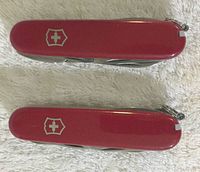 Top and bottom view showing red handles with Victorinox white cross logo on each Swiss Army knife.