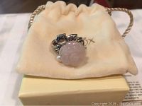 Close-up of Lenox sterling silver ring showing pink quartz flower with garnet and pearl accents on a drawstring pouch